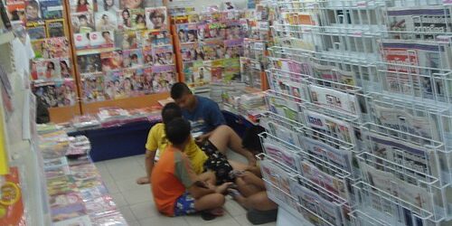 Thai Young people Thai children sitting on the floor of a convenience store reading magazines from the rack.