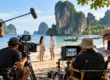 Conceptual AI illustration of an international film crew working on a Thai coastal production set with cameras and sound equipment