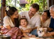 Thai-Western family with a baby, Thai grandparents and a small dog smiling together on the veranda of a traditional Thai house. AI-generated image.