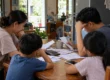 Worried Thai family with two children going over bills with a calculator at the kitchen table. AI-generated image.