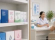 Clinic shelf with generic condom boxes in the foreground while a nurse gives sexual health advice to a woman at a desk in the background. AI-generated image.