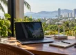 Laptop, router and notebook on a desk overlooking a Thai coastal city, illustrating web hosting for a Thailand-based website. AI-generated image.